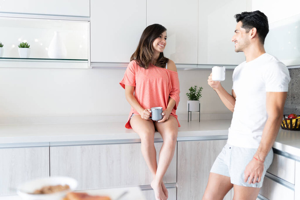 Щаслива молода пара розмовляє під час пиття кави вранці вдома
 - Фото, зображення