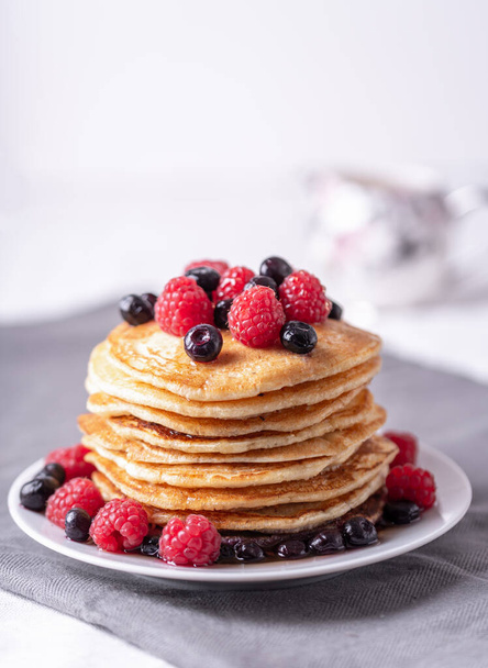 Homemade pancakes with raspberries and blueberries on grey napkin. - Photo, image