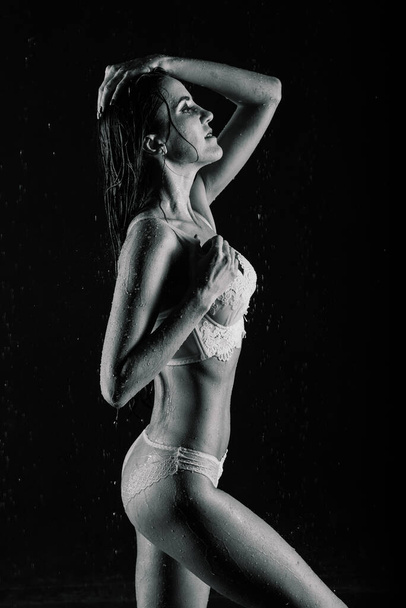 Junge Frau mit prachtvollem Körper in weißen Dessous mit Wassertropfen im Aquastudio - Foto, Bild