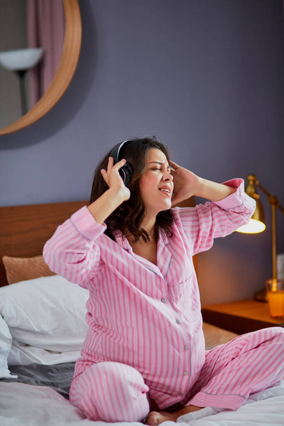 beautiful cute pregnant woman listening to music on bed - Foto, Bild