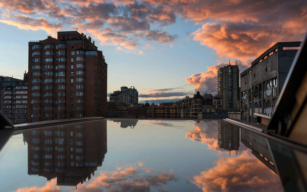 Dramatic sunset sky with pink clouds after the storm in the city, view from the window with reflection - Photo, Image