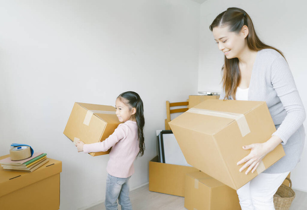 Feliz joven madre asiática y su hija niña con cajas de cartón en casa nueva en el día de la mudanza. Nuevo concepto de vivienda, préstamo e hipoteca inmobiliaria. - Foto, imagen