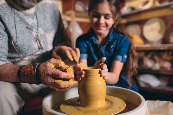 Pottery workshop. Grandpa teaches granddaughter pottery. Clay modeling - Photo, image