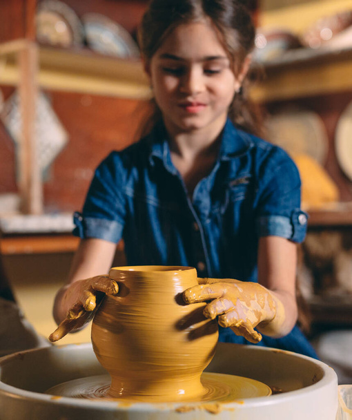Pottery workshop. A little girl makes a vase of clay. Clay modeling - Fotó, kép