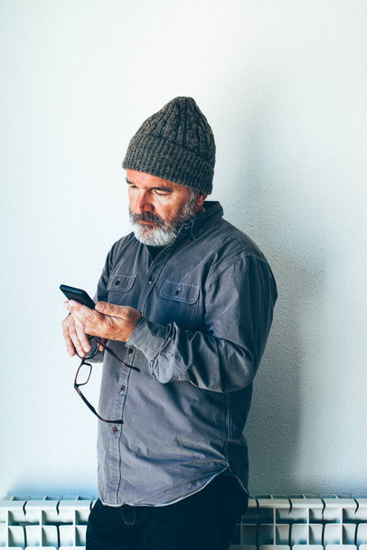 Uomo con barba e cappuccio utilizzando uno smartphone - Foto, immagini