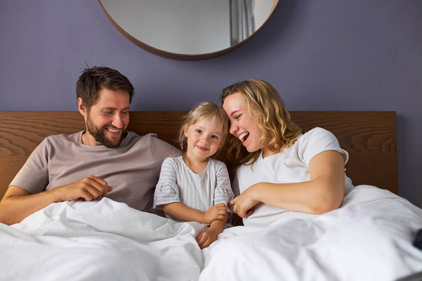 happy family with child girl laugh lying on bed in the morning - Fotoğraf, Görsel