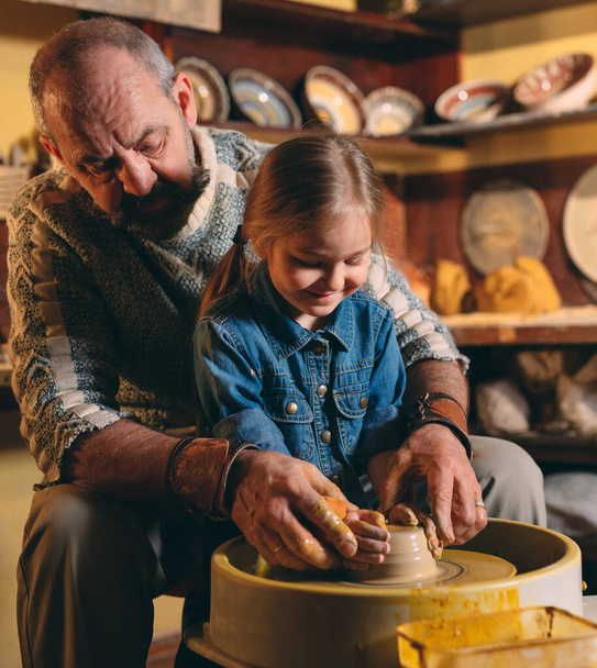 Pottery workshop. Grandpa teaches granddaughter pottery. Clay modeling - Fotó, kép