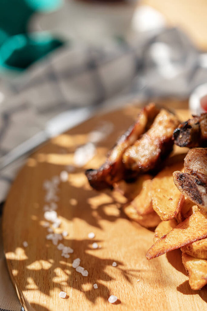 ruoka valokuvaus grillattua lihaa Ranskalaiset perunat kahvilassa kirkas Aurinkoinen luonnonvalo ja varjo kasvien lehdistä - Valokuva, kuva