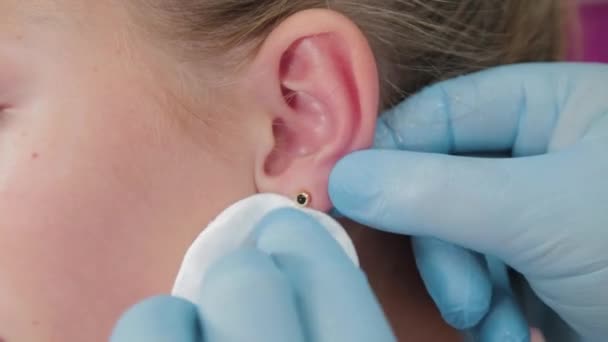 Ärztin führt Ohrenpiercing-Verfahren für Mädchen durch. - Filmmaterial, Video