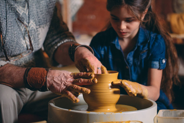 Pottery workshop. Grandpa teaches granddaughter pottery. Clay modeling - Фото, изображение