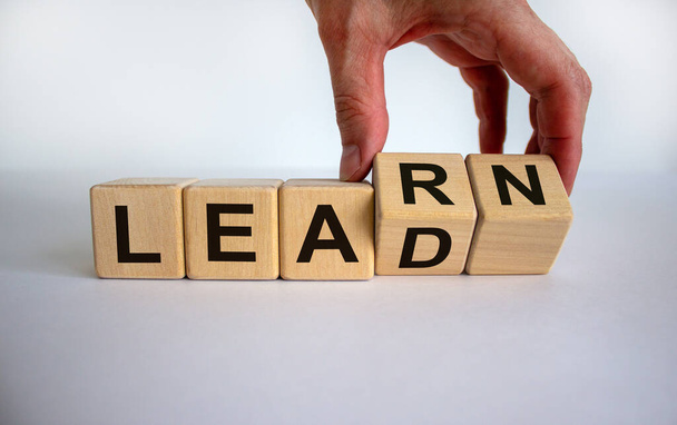 Hand is turning a cubes and changes the word 'learn' to 'lead' or vice versa. Beautiful white background, copy space. Business concept. - Fotó, kép