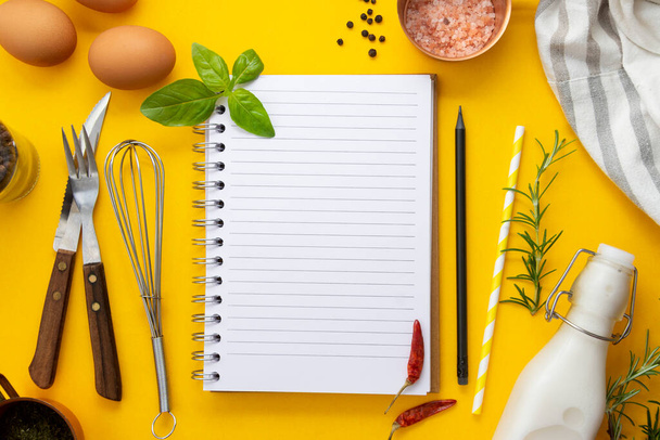 Open blank notebook for recipes, yellow background, food ingredients and utensils for cooking. Copy space. - Foto, Imagen
