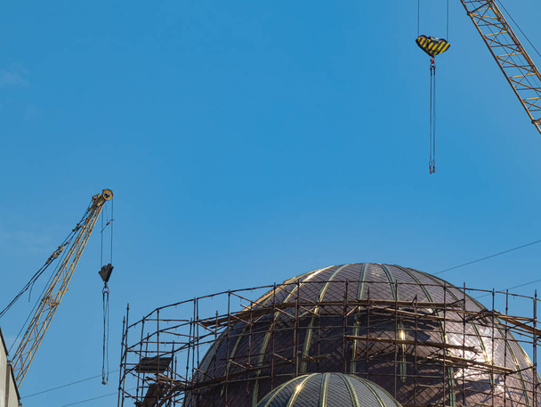 Színpad az ortodox egyház aranyozott kupolájának építésében és telepítésében. Munkaterület, melyet leszerelhető állványzat alkot. A daruk indulásra készen állnak. - Fotó, kép