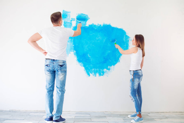 Happy couple painting walls in their new house ready for living together. - Photo, image