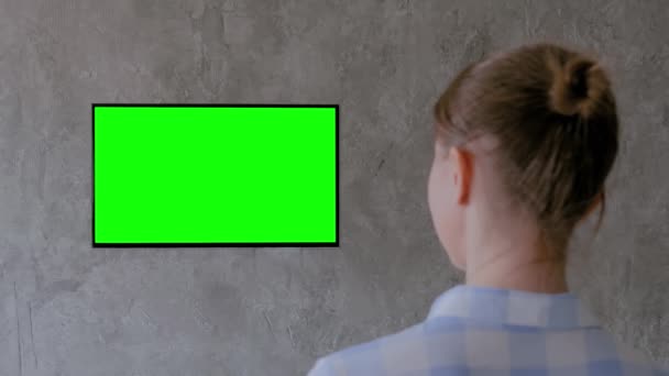 Koncept zelené obrazovky - žena sledující ploché smart led TV se zeleným displejem - Záběry, video