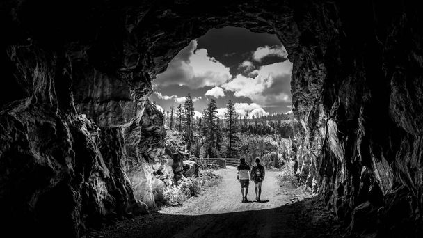Foto in bianco e nero di un tunnel della ferrovia abbandonata Kettle Valley scavata nelle rocce del Myra Canyon vicino a Kelowna, Columbia Britannica, Canada - Foto, immagini