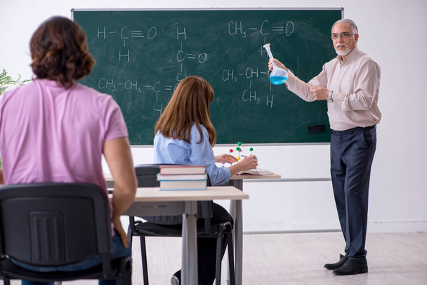 Vecchio insegnante di chimica e due studenti in classe - Foto, immagini