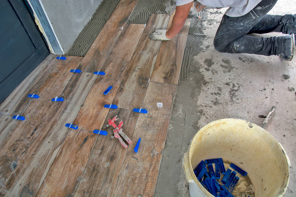 The master precisely glues new floor tiles. The panels look like laminate. - Photo, Image