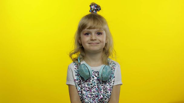 Χαρούμενο παιδί χαμογελά, αισθάνεται ανέμελη χαρούμενη αφού άκουσε αστείο, ανόητο αστείο στο κίτρινο φόντο - Φωτογραφία, εικόνα