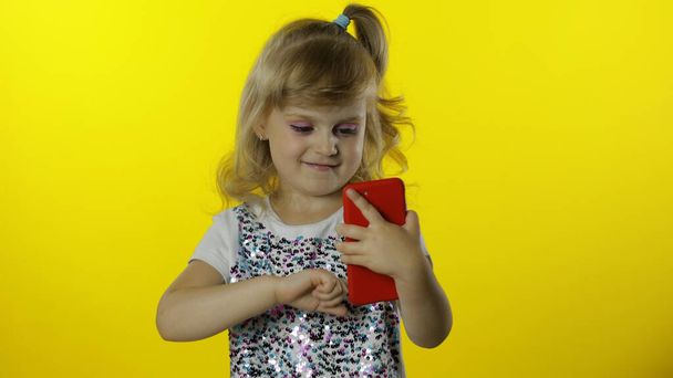 Gyermek lány görgetés szociális hálózati hozzászólások okostelefon. Távoli online vásárlás, böngészés telefonon. - Fotó, kép