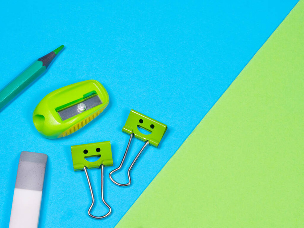  Crayon vert, gomme, clips de reliure sourire sur fond bleu - Photo, image
