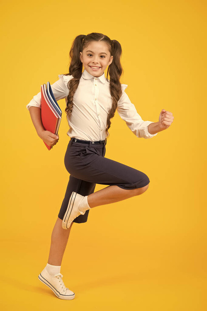 An inspirational literature. Adorable little girl running with books of English literature on yellow background. Cute small child enjoy reading childrens literature. Preparing for a literature exam - Foto, Imagem