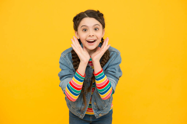 Excited surprised little girl with braids wear denim clothes, childhood dreams concept - 写真・画像
