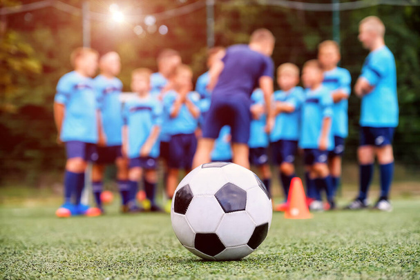 Bola de fútbol y equipo de fútbol juvenil borrosa con entrenador en el campo - Foto, imagen