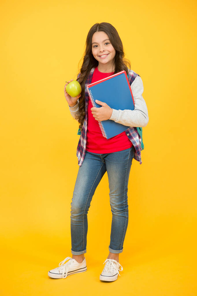 Eat good food to be cute. Happy girl hold apple and books. Brain food. School snack. Healthy eating habits. Natural food. Mental wellbeing. Cognitive health. Learning and development. Childs diet - Foto, Imagen