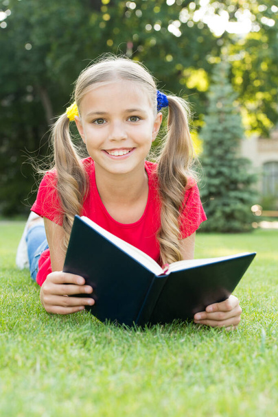 Small girl cute hairstyle reading book relaxing nature background, smart schoolgirl concept - Φωτογραφία, εικόνα