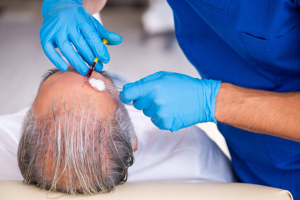 Anciano visitando joven doctor masculino en cono de trasplante de cabello - Foto, Imagen