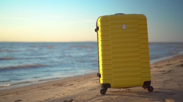 Ein gelber Koffer steht am Strand vor dem Hintergrund des Meeres. Reisekoffer. - Filmmaterial, Video