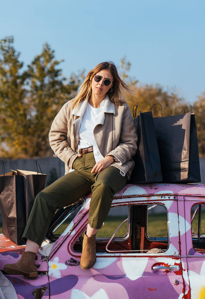 Young woman sits on an old decorated car - Photo, image