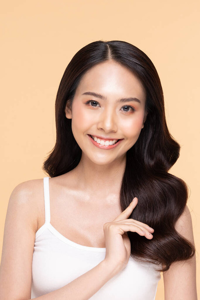 Beautiful Asian young woman touching hairs smile with clean fresh skin Happiness and cheerful with positive emotional,isolated on Beige background,Beauty Cosmetics and Facial treatment Concept - Foto, Bild