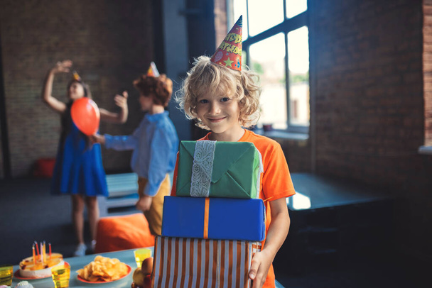 Cute blonde boy holding presents and smiling - Foto, afbeelding