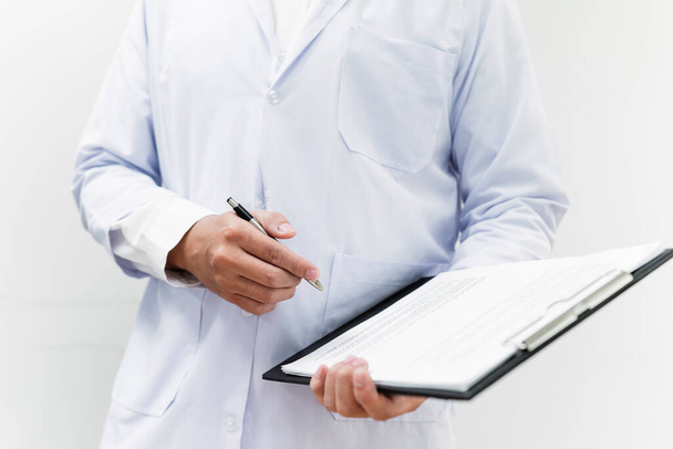 Cropped image of progress note on clipboard in doctor's hands while he write the patient's condition. - Фото, зображення