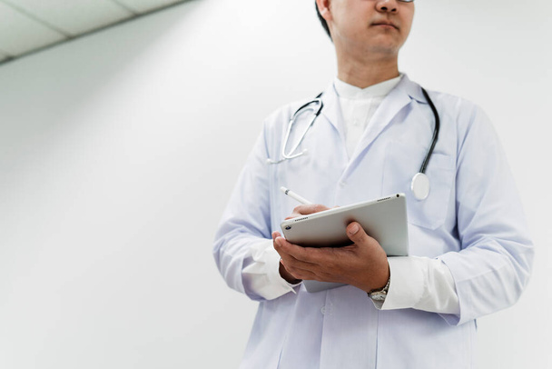 Низкоугольный снимок мужчины-врача держит планшет в руках, чтобы проверить медицинскую историю пациента и записать. - Фото, изображение