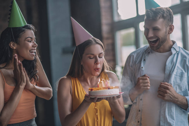 Woman blowing out candles on her birthday cake - Φωτογραφία, εικόνα