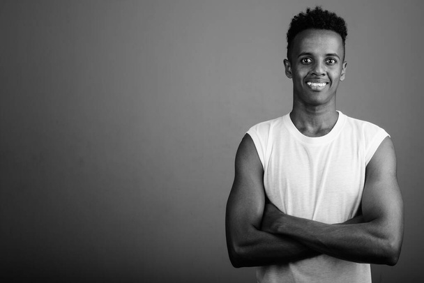 Studio shot of young handsome African man ready for gym against gray background in black and white - Photo, image