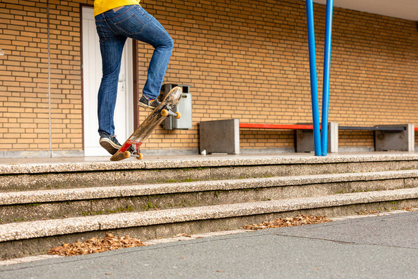 A male person doing skateboard trick stunts on the stairs during autumn - Photo, image