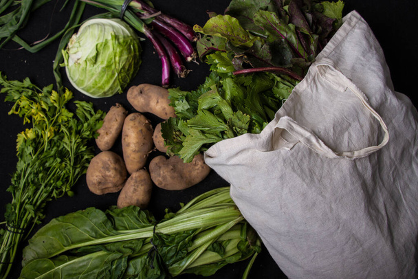 A closeup shot of assorted vegetables with a white eco bag isolated on a dark background - Foto, immagini