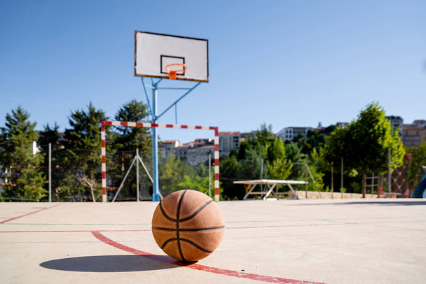 A basketball on a basketball court with the basket in the background - Fotoğraf, Görsel