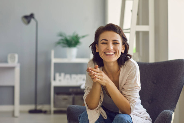 Online-Kommunikation. Glückliche junge Frau lächelt in die Kamera, während sie mit jemandem im Web vom Home Office aus spricht - Foto, Bild