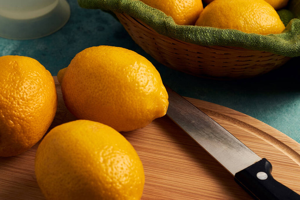 A closeup shot of lemons on a wooden cutting board and in a basket - Photo, image