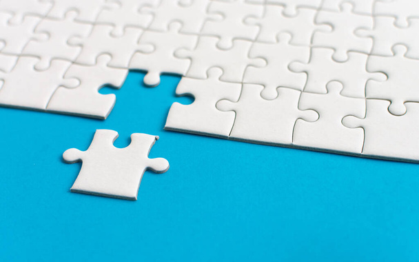 White jigsaw puzzle on blue background. Team business success partnership or teamwork. - Photo, Image