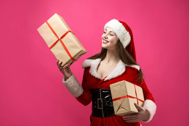 サンタのコスチュームを着た美しくセクシーな女性。女の子はクリスマスプレゼントを持ってる. - 写真・画像