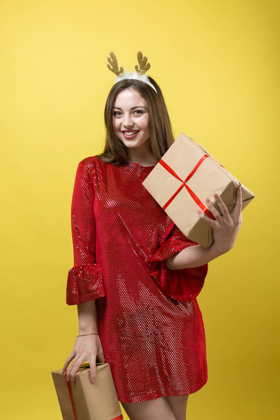 Tyttö punaisessa mekossa lahjoja keltaisella taustalla. - Valokuva, kuva