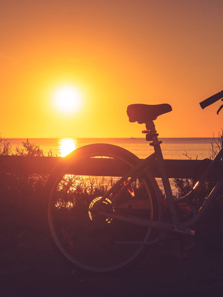 Bicycle outdoor parked on beach, evening time, sunset sky. Holidays, sport and recreation. - Foto, immagini