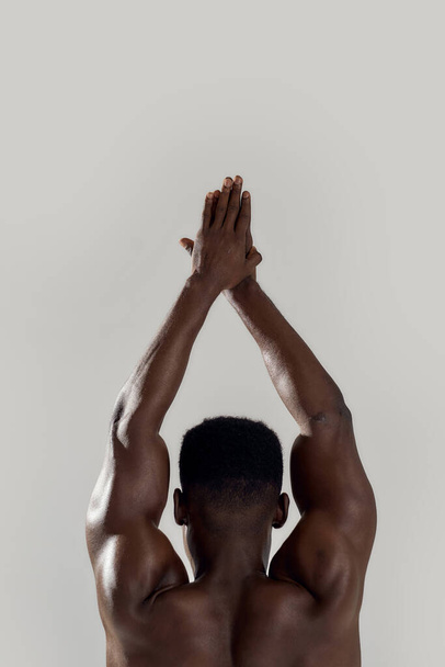 Rear view of muscular african american man with naked torso standing with his hands joined above his head. Swimmer about to dive isolated over grey background. Sports, swimming - Photo, Image