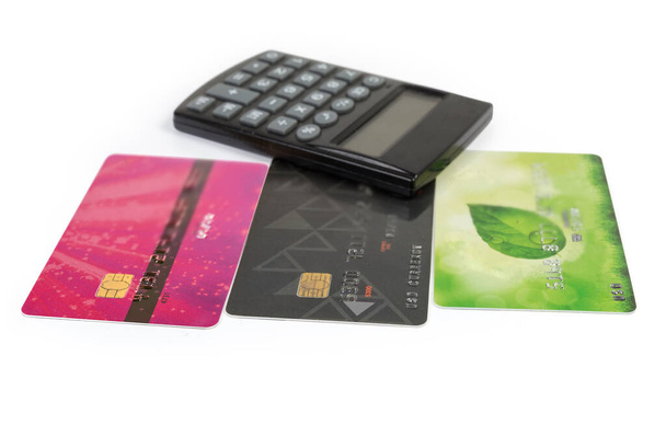 Diferentes cartões bancários de plástico em um fundo turvo de calculadora de bolso eletrônico em um fundo branco, close-up em foco seletivo
 - Foto, Imagem